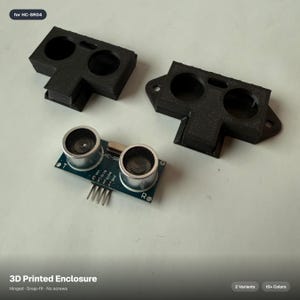 May include: Black 3D printed enclosures and an HC-SR04 ultrasonic sensor. The enclosures have two circular openings and a rectangular base. The sensor is on a green circuit board with silver components. Text on the image reads "3D Printed Enclosure".