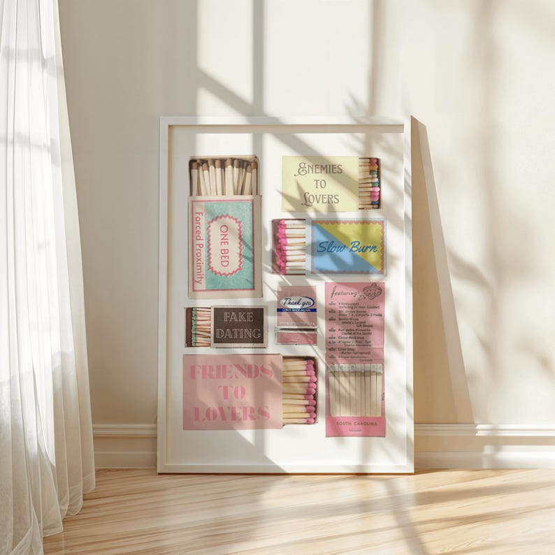 Puede incluir: Una impresi&oacute;n art&iacute;stica enmarcada que presenta cajas de cerillas con textos como "Enemies to Lovers" y "Fake Dating". Las cajas de cerillas son de varios colores, incluyendo rosa, azul y amarillo, sobre un fondo blanco.