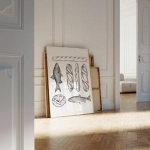 Puede incluir: Una ilustraci&oacute;n en blanco y negro de una baguette, pescado y pan sobre un fondo blanco. La ilustraci&oacute;n est&aacute; enmarcada y colgada en una pared blanca.