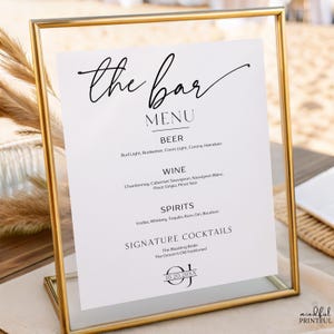 May include: A gold-framed bar menu with a white insert. The menu lists beer, wine, spirits, and signature cocktails. The text "the bar MENU" is at the top in elegant script. The date "10.20.20XX" is at the bottom.