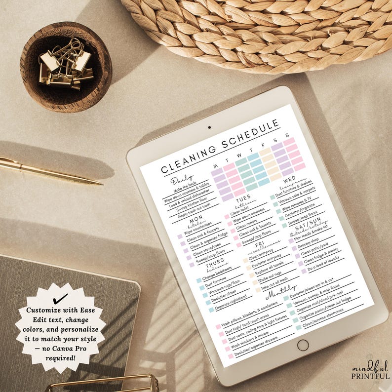 May include: A digital tablet shows a cleaning schedule with tasks for each day of the week, in pastel colours. The text reads "Cleaning Schedule". A wooden bowl with gold paper clips and a gold pen are also visible.