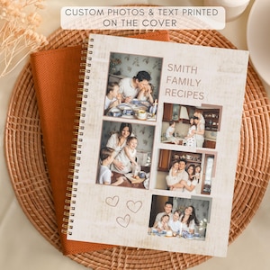 Op de afbeelding: Een spiraalgebonden receptenboek met familiefoto's en de tekst "Smith Family Recipes". De kaft heeft een lichte, verweerde houtuitstraling. Het boek ligt op een geweven mat, met oranje stof eronder.