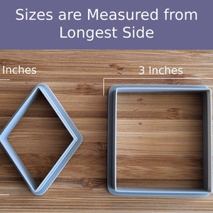 May include: Two cookie cutters on a wooden surface. The cookie cutters are 3 inches in size. One is a square shape and the other is a diamond shape.