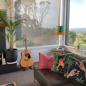 May include: A white ceramic mug with a black handle and the text "But First, Coffee" in a bold, black font. The mug is set against a blurred background, suggesting a cozy setting.