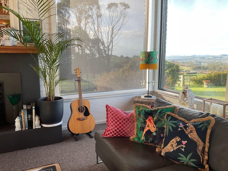 May include: A white ceramic mug with a black handle and the text "But First, Coffee" in a bold, black font. The mug is set against a blurred background, suggesting a cozy setting.