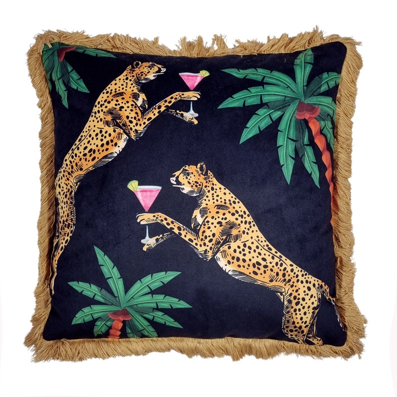 May include: Black velvet pillow with a fringed border featuring a tropical print of two cheetahs holding cocktails and palm trees.