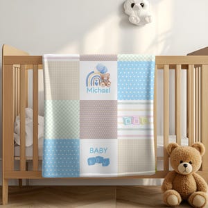 May include: A blue and beige baby blanket with a patchwork design. The blanket features a rainbow, a teddy bear, and the words "Michael" and "Baby Boy".