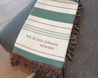 May include: A personalized throw blanket with a striped pattern in white, green, and red. The blanket has a fringed edge and features the text "Mr & Mrs Johnson" and the date "05/20/2025".