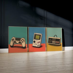May include: A set of three framed wall art prints featuring illustrations of vintage and modern video game controllers. The first print shows a beige game controller, the second a handheld console, and the third a rectangular game controller.