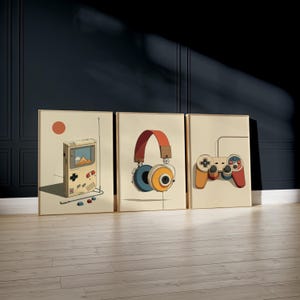 May include: Three framed art prints featuring retro gaming themes. The prints depict a handheld game console, headphones, and a game controller, all in a vintage cartoon style with a beige background and a warm color palette.