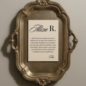 May include: A silver-toned, ornate tray holds a cream-coloured card with the name "Aliza R." in elegant script. The card includes instructions to add event details. The tray has handles and a decorative border.