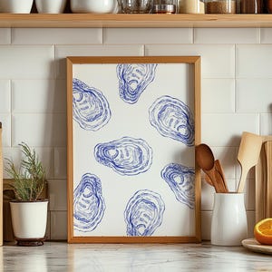 Può includere: Una stampa incorniciata con sfondo bianco e illustrazioni blu di ostriche. La stampa è in una cornice di legno.