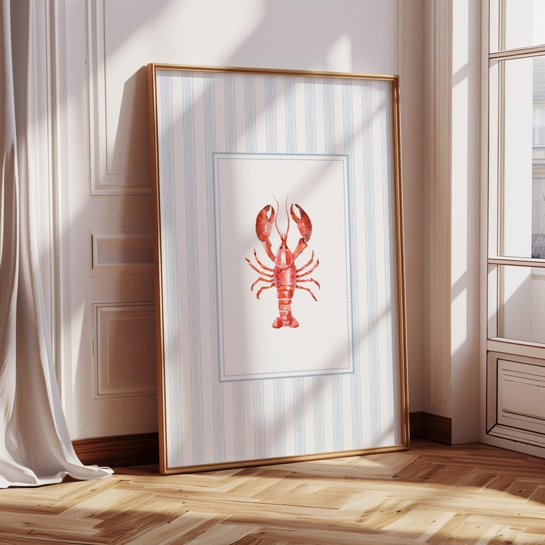 Puede incluir: Una impresi&oacute;n art&iacute;stica enmarcada con una ilustraci&oacute;n de acuarela de una langosta roja. La impresi&oacute;n tiene un fondo a rayas azules y blancas con un borde azul claro. El marco es dorado.