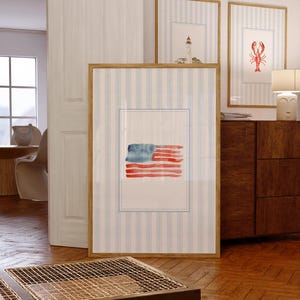 Puede incluir: Pinturas de acuarela enmarcadas con temas n&aacute;uticos. La imagen principal es una bandera americana. Otras obras enmarcadas incluyen un faro y una langosta. Los marcos tienen un acabado de madera clara.