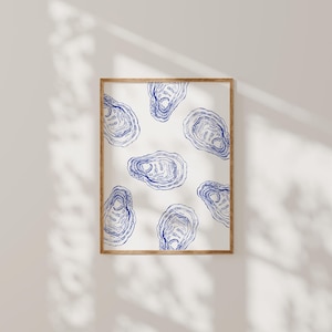 Puede incluir: Una impresión enmarcada con fondo blanco y un patrón repetido de conchas de ostras azules.