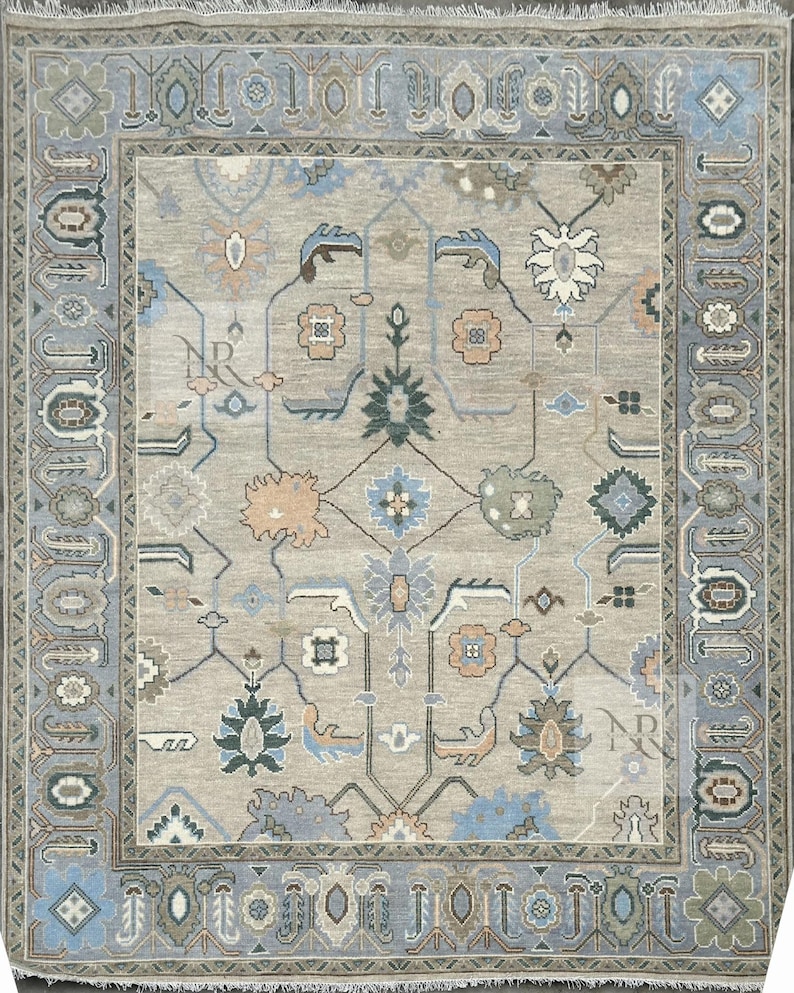K&ouml;nnte beinhalten: Ein beiger Teppich mit einem blauen und gr&uuml;nen geometrischen Muster. Der Teppich hat einen Fransenrand.