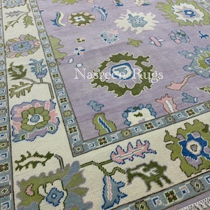 May include: A rectangular rug with a lavender central field and a cream border. The rug displays floral and geometric patterns in green, blue, and pink. The text "Nasreen Rugs" is visible on the rug.