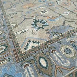 K&ouml;nnte beinhalten: Ein hellblauer und beiger Teppich mit traditionellem persischem Design. Der Teppich zeigt komplizierte florale Muster und geometrische Formen in Blaut&ouml;nen, Beige und Gr&uuml;n.