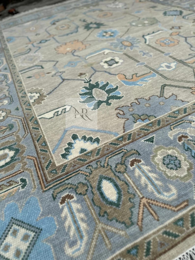 K&ouml;nnte beinhalten: Ein hellblauer und beiger Teppich mit traditionellem persischem Design. Der Teppich zeigt komplizierte florale Muster und geometrische Formen in Blaut&ouml;nen, Beige und Gr&uuml;n.