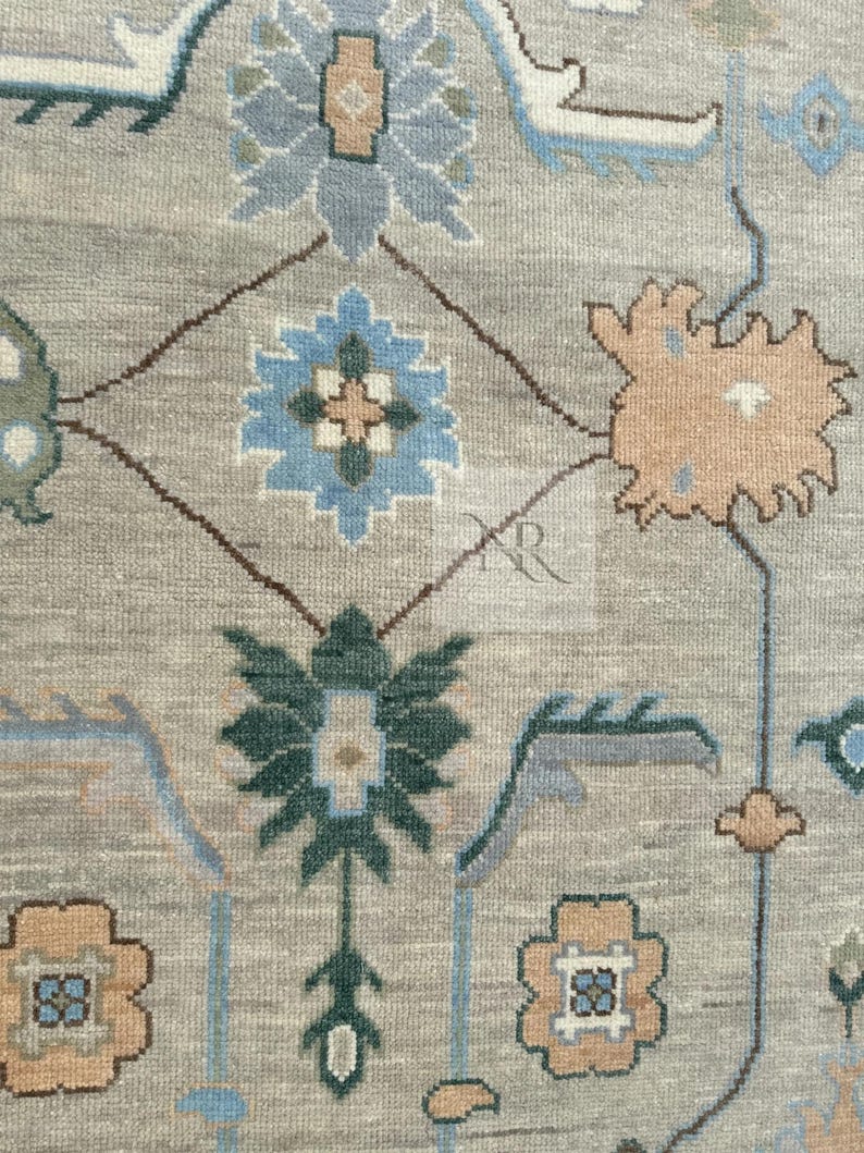 K&ouml;nnte beinhalten: Ein beiger Teppich mit einem sich wiederholenden Muster aus blauen, gr&uuml;nen und braunen floralen Motiven. Der Teppich hat einen dezenten Used-Look.