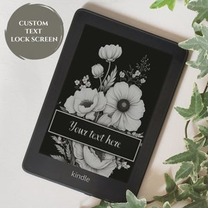 May include: Black Kindle e-reader with a floral design lock screen. The screen displays a black and white illustration of flowers with the text "Your text here" on a black banner. The words "Custom Text Lock Screen" are in a gray circle.