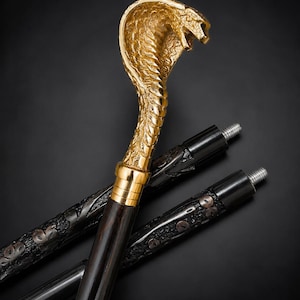 May include: A walking stick featuring a gold-coloured cobra head handle with detailed scales. The shaft is made of dark wood with a smooth finish, and the handle connects to a black, textured, segmented shaft section with a threaded metal screw top.