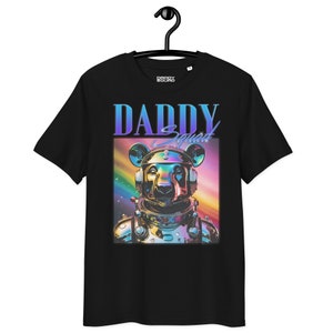 May include: Black t-shirt featuring a graphic of a metallic bear wearing an astronaut helmet. The bear is surrounded by a rainbow and stars. The text "Daddy Squad" is printed above the bear.