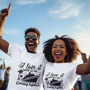 May include: A couple wearing white t-shirts with a cruise ship graphic and the text "I love it when we are cruising together". They are smiling and raising their arms in the air.