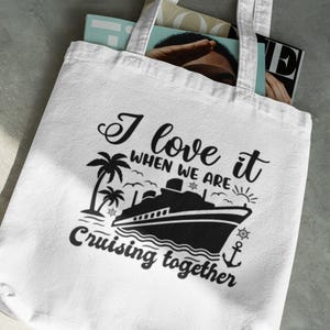 May include: White tote bag with black text and a graphic of a cruise ship and palm trees. The text reads "I love it when we are cruising together."