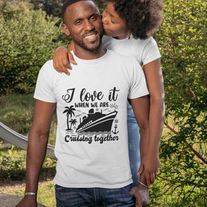 May include: A white t-shirt with a black graphic of a cruise ship and palm trees. The text on the shirt reads "I love it when we are cruising together".