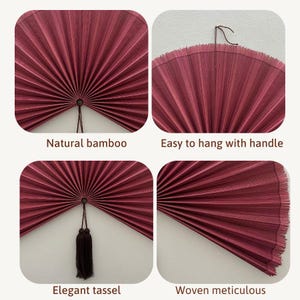 May include: A circular wall fan made of dark red woven bamboo material. The fan features a central pivot point, a dark brown hanging cord, and a dark brown decorative tassel. The text in the image includes Natural bamboo, Easy to hang with handle, Elegant tassel, and Woven meticulous.