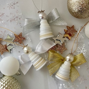 May include: White and gold Christmas ornaments shaped like angels. The angels are made of buttons and have a white, gold, and silver colour scheme.