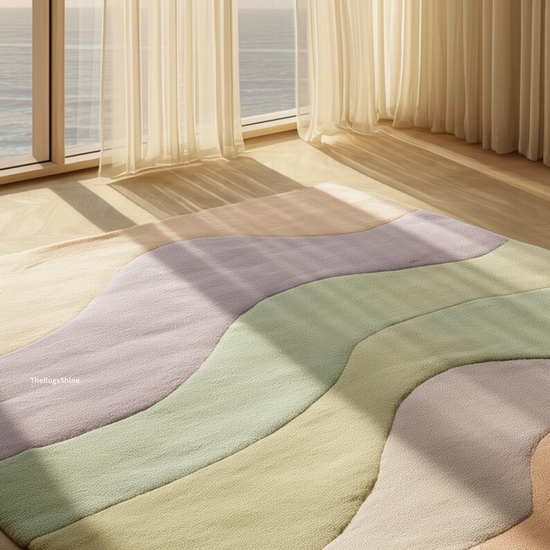 May include: A pastel-colored area rug with a wavy design. The rug features bands of lavender, green, and peach hues. The rug is placed on a wooden floor near a window with sheer curtains. The text "TheRugsShine" is visible.