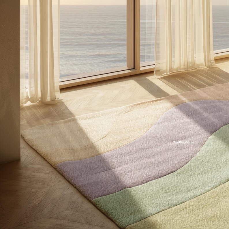 May include: A pastel-colored area rug with a wavy design. The rug features bands of light yellow, lavender, and light green. The rug is placed on a wooden floor near a window with sheer curtains.