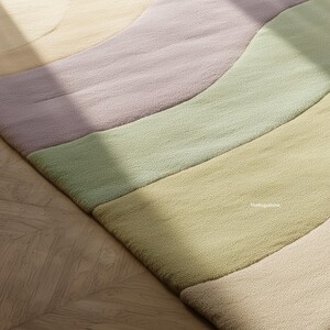 May include: A close-up of a colorful rug with a wavy design. The rug features pastel colors, including lavender, green, and yellow. The rug is made of a soft, textured material and is placed on a wooden floor.