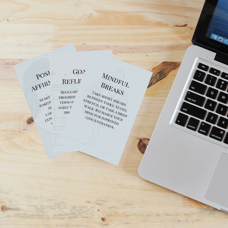 Peut inclure: Trois cartes blanches avec du texte bleu sur une surface en bois. Les cartes sont intitul&eacute;es "Affirmations Positives", "R&eacute;flexion sur les Objectifs" et "Pauses Conscientes". Le texte sur les cartes comprend des phrases comme "Commencer Positif", "Progr&egrave;s R&eacute;gulier" et "Prendre de Courtes Pauses Entre les T&acirc;ches". Un ordinateur portable argent&eacute; se trouve dans le coin sup&eacute;rieur droit de l'image.
