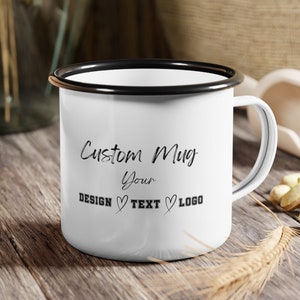 Op de afbeelding: Witte emaille mok met een zwarte rand en handvat. Op de mok staat de tekst "Custom Mug Your DESIGN ♥ TEXT ♥ LOGO".