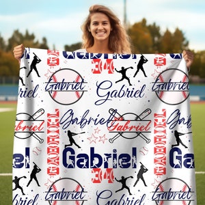May include: White baseball-themed blanket with red and blue accents. The blanket features the name "Gabriel" repeated throughout the design, along with baseballs, bats, and stars.
