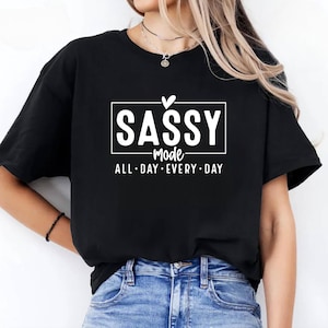 Könnte beinhalten: Schwarzes T-Shirt mit weißem Text, der "SASSY mode ALL DAY EVERY DAY" lautet, mit einem Herzen über dem Wort "SASSY".