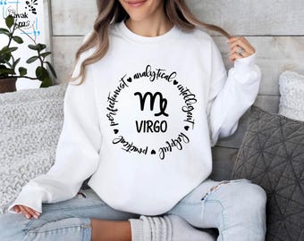 Op de afbeelding: Wit sweatshirt met een zwarte cirkelvormige afbeelding met het sterrenbeeld Maagd en de woorden "analytisch", "intelligent", "perfectionistisch", "praktisch", "behulpzaam", "trouw" en "Maagd".