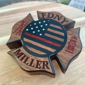 May include: Wooden FDNY firefighter's cross with an American flag, red line, and the name Miller.