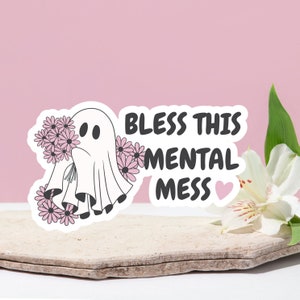 May include: A white ghost holding a bouquet of pink flowers with the text "Bless this mental mess" and a pink heart.