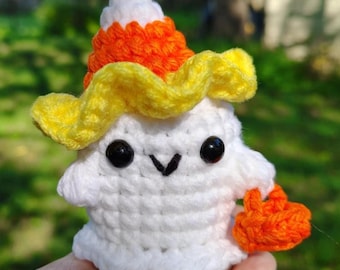 Könnte beinhalten: Ein handgefertigtes, weißes Häkelgespenst mit einem Candy-Corn-Hut und einer orangefarbenen, kürbisförmigen Tasche. Das Gespenst hat schwarze Knopfaugen und einen gestickten Mund. Der Hut ist weiß, orange und gelb.