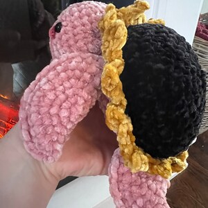 May include: A pink crocheted turtle with a black crocheted shell and a gold crocheted flower around the shell.