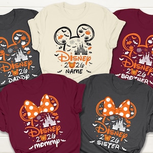 May include: Five short-sleeved t-shirts with Halloween-themed Disney designs. Each shirt features a Mickey Mouse ear outline with pumpkins, bats, and a castle. Text includes "Disney 2026" and family member names like "Daddy" and "Mommy."