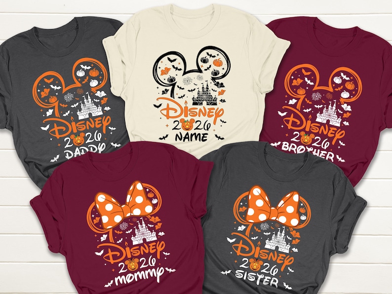 May include: Five short-sleeved t-shirts with Halloween-themed Disney designs. Each shirt features a Mickey Mouse ear outline with pumpkins, bats, and a castle. Text includes "Disney 2026" and family member names like "Daddy" and "Mommy."