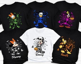 May include: Five black t-shirts with different Disney characters dressed as skeletons for Halloween. The characters are Mickey Mouse, Minnie Mouse, Donald Duck, Goofy, and Pluto. The shirts have the words "Mommy", "Daddy", "Auntie" printed on them.