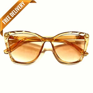 Puede incluir: Gafas de sol de ojo de gato de color ámbar con montura transparente y lentes marrones.