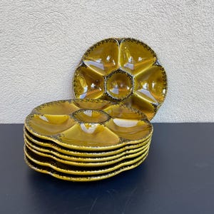 May include: Set of six yellow ceramic oyster plates with a black rim. The plates are stacked on top of each other.