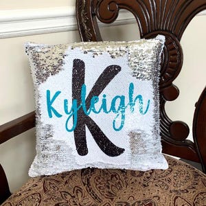 May include: White sequin pillow with a black letter K and the name "Kyleigh" written in turquoise.